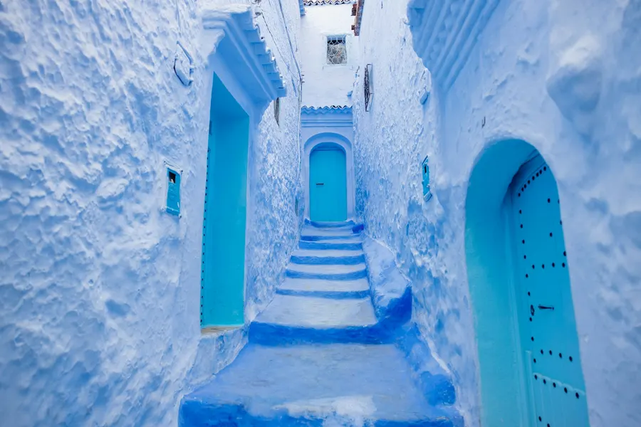 Narrow blue stairway alley with traditional studded doors in Chefchaouen