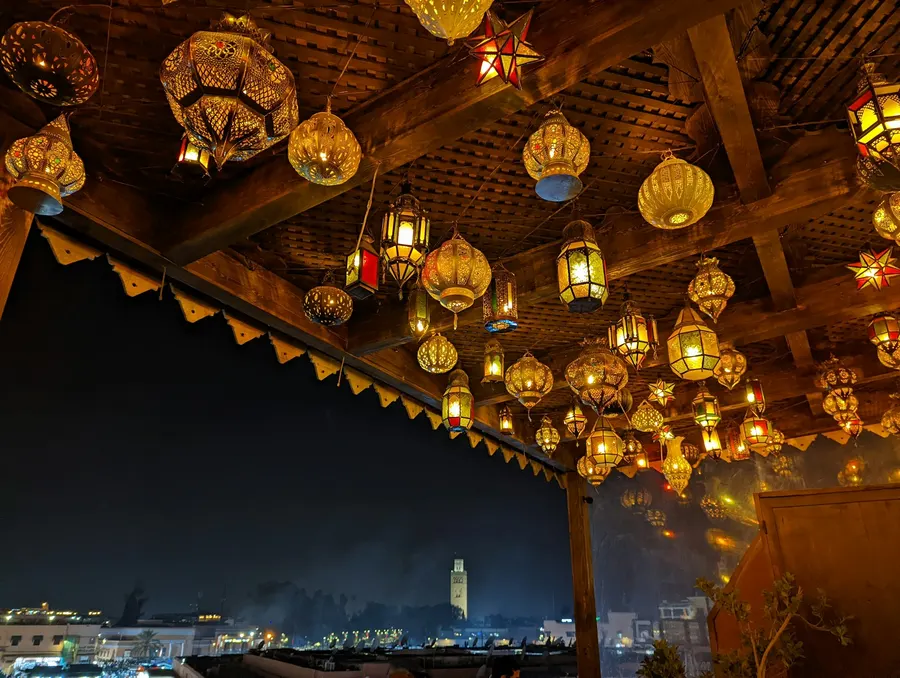 Glowing brass Moroccan lanterns hanging on a rooftop terrace at night