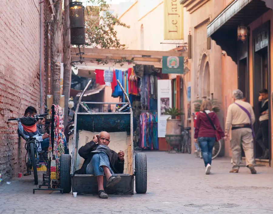 Local resident resting with a handcart in a Marrakech medina street