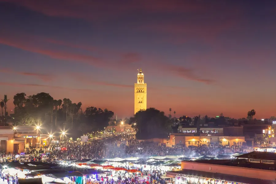 Illuminated Jemaa el-Fnaa night market with Koutoubia minaret in Marrakech