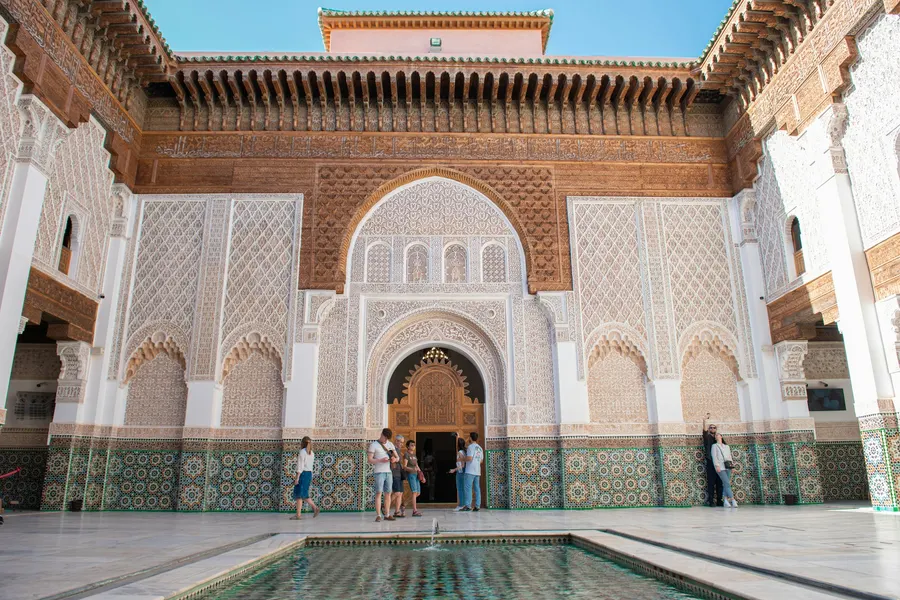 Visitors in the carved marble courtyard of Ben Youssef Madrasa