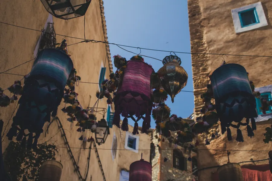Colorful hanging fabric lanterns in a stone alley in Chefchaouen