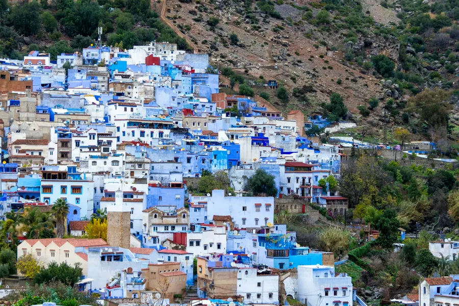 Blue-washed hillside houses of Chefchaouen surrounded by green mountains
