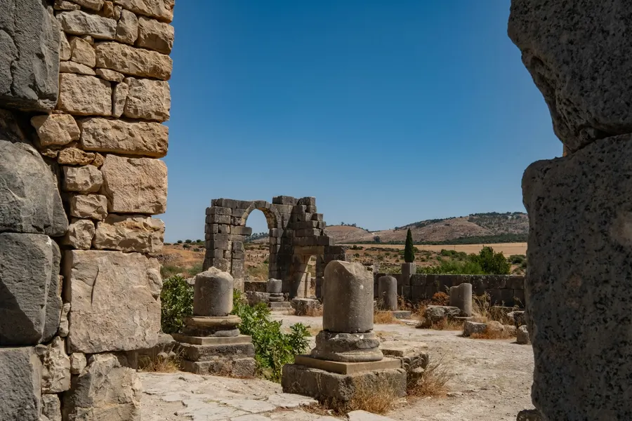 Ancient Roman columns and stone ruins at Volubilis through an archway