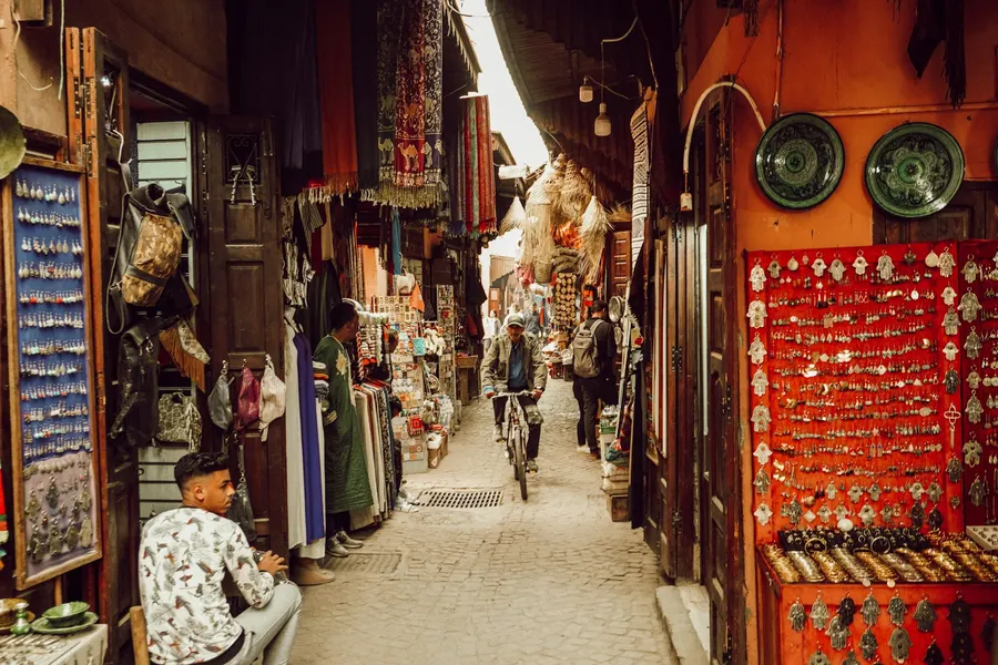Bicycle rider passing through a bustling artisan souk in Marrakech