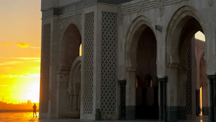Sunset glow behind the Moorish arches of Hassan II Mosque