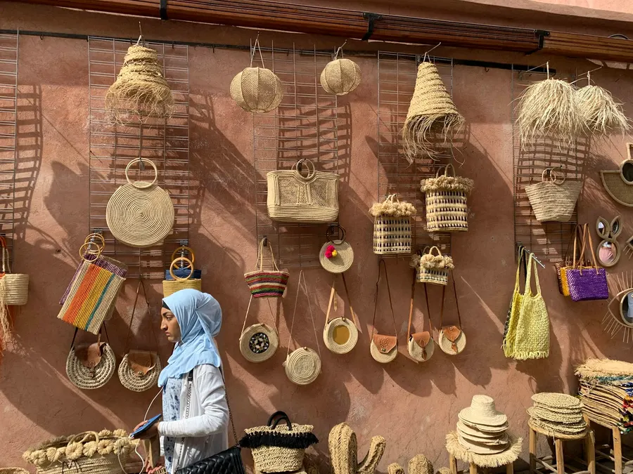 Woven straw bags and artisan handicrafts on a terracotta wall in Marrakech