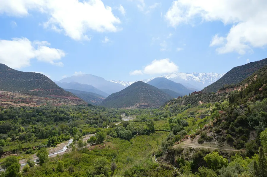 Green valley and mountain stream with snow-capped High Atlas peaks