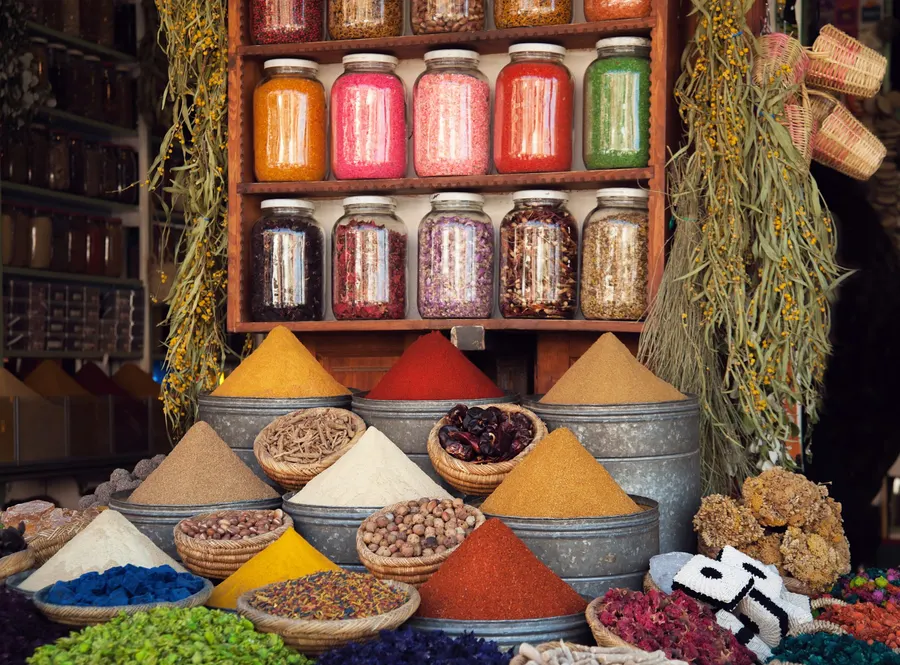 Colorful spice pyramids and glass jars in a traditional Moroccan souk