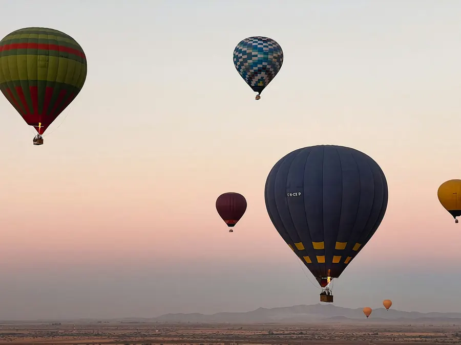 Globos aerostáticos flotando sobre la llanura del palmeral de Marrakech al amanecer