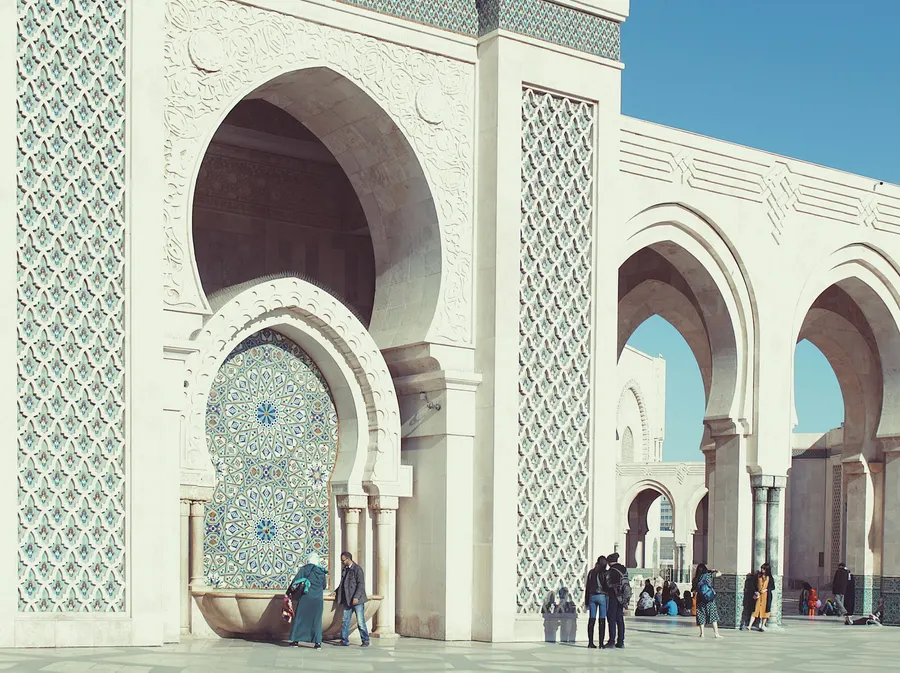 Arcos ornamentados de herradura y fuente de mosaico en el patio de la Mezquita Hassan II